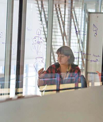 Student writing on glass wall