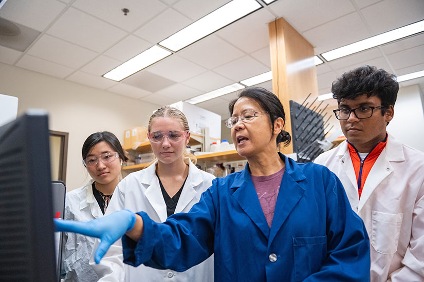 Faculty member in lab with a group of students.