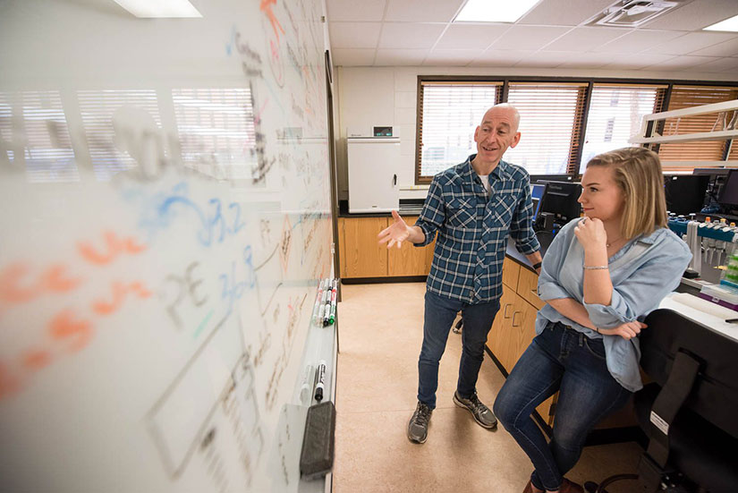 Teacher and student discussing research in conference room.