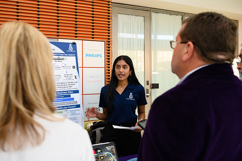 Female student explaining project design to audience.