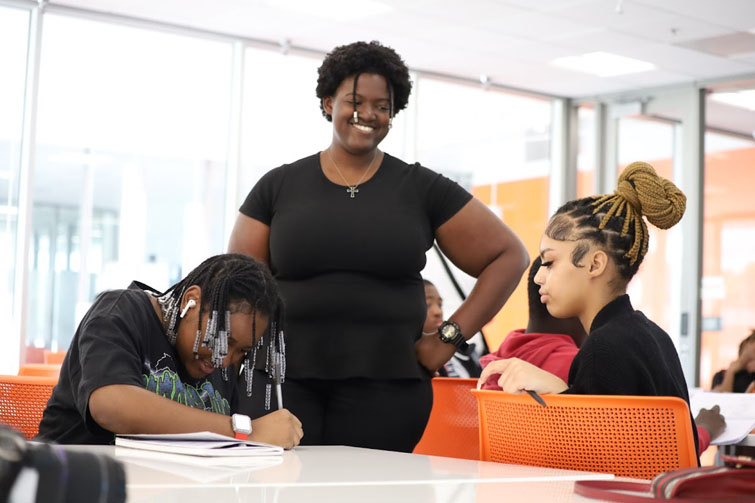 Teacher smiling as she helps two students