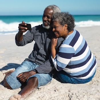 Man and woman on a beach taking a photo.