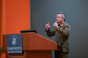 A speaker in military attire gestures while presenting at the Clemson Institute for the Study of Capitalism.