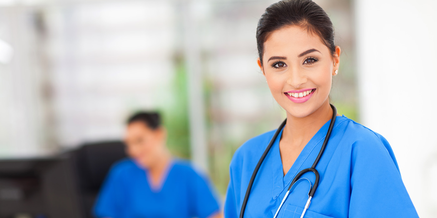 Woman wearing blue scrubs in hospital setting.