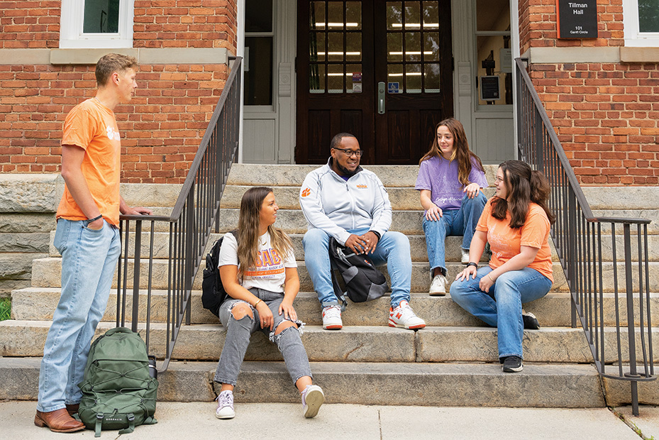 Group of college students sitting together on stairs, engaged in conversation.