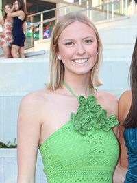 A young woman in a green dress poses in front of outdoor stairs.