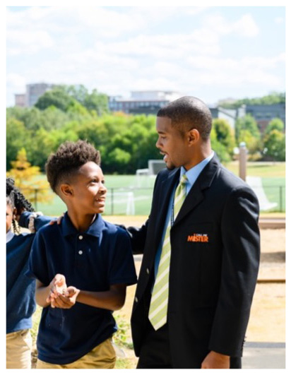 A professional man in a suit interacts with two children at a playground, promoting a welcoming atmosphere for youth engagement.