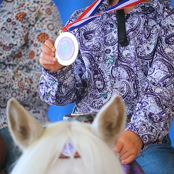 horse rider sitting on a horse and showing their medal