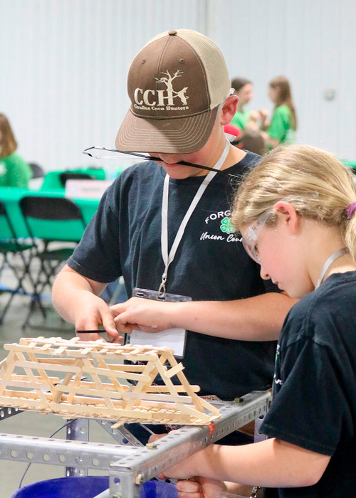 two kids working on their bridge made of chopsticks