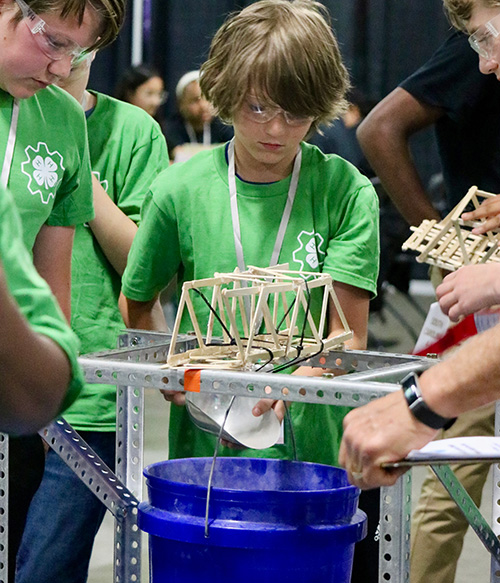 two kids working on their bridge made of chopsticks