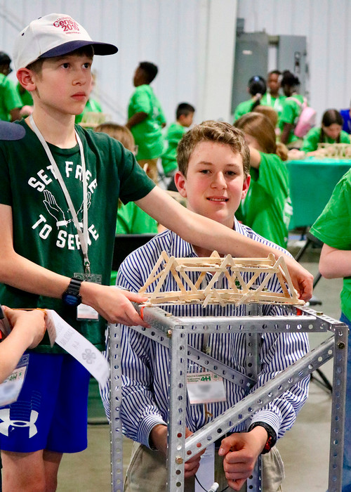 two kids working on their bridge made of chopsticks