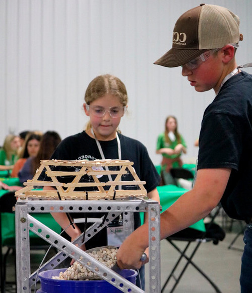 two kids working on their bridge made of chopsticks