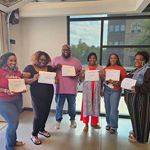 Six people standing side by side holding certificates