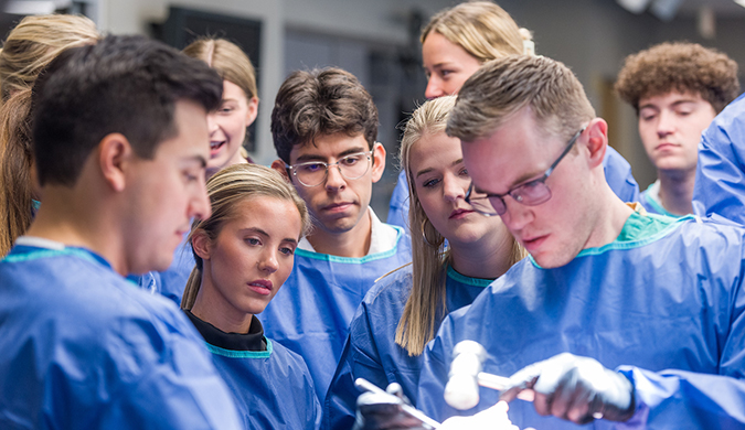 A group Clemson students viewing a representative orthopedic procedure experience simulator.