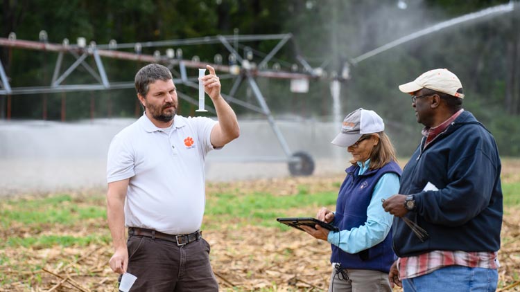 three researchers examine a water sample in the feild at edisto rec