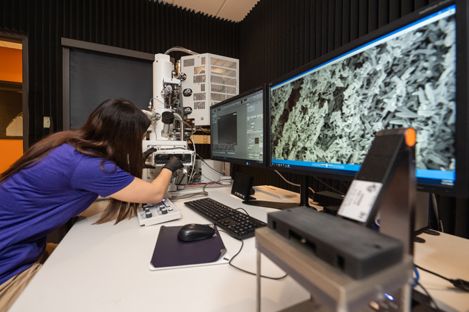 a student examines a sample under an electron microscop