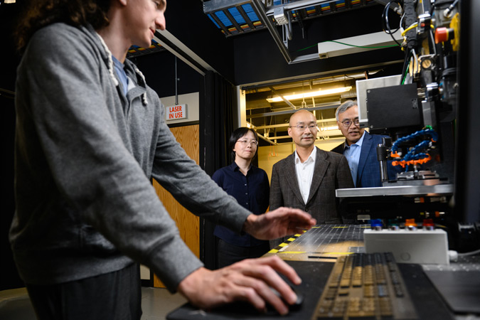 a student uses a facility computer while industry members look on