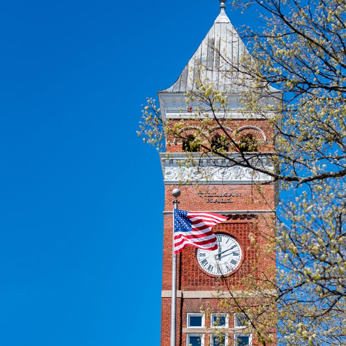 The american flag flies in front of the Tillman Hall Clock Tower.