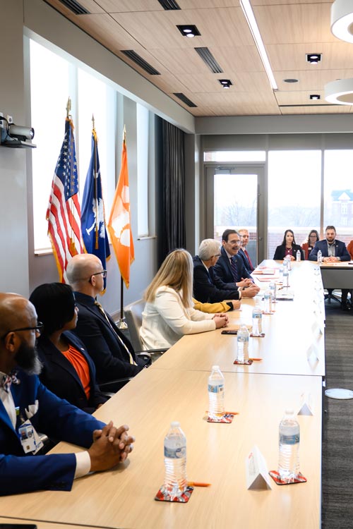 A table of leadership meet with a visiting official.