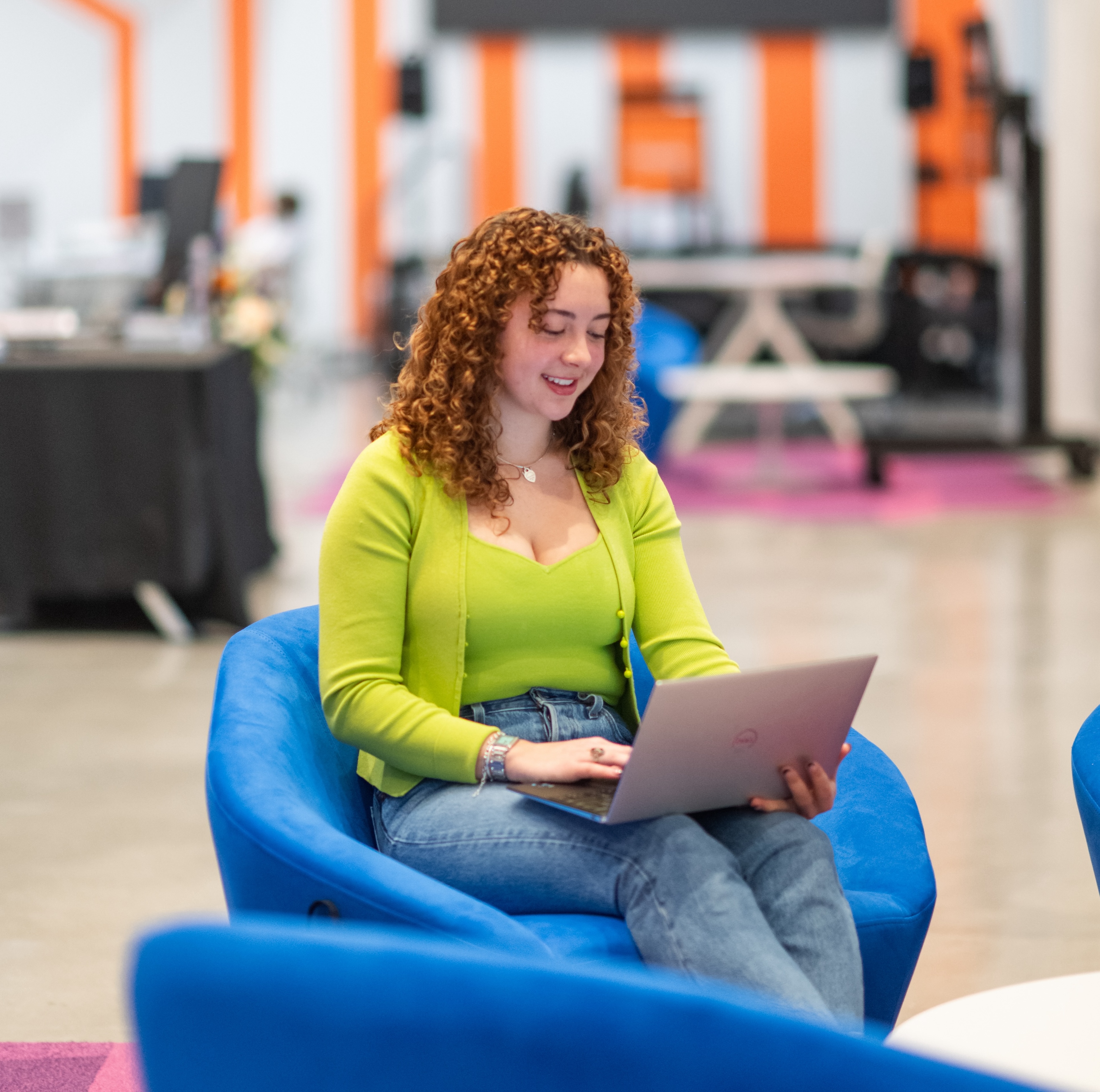a student sits in blue chair with laptop