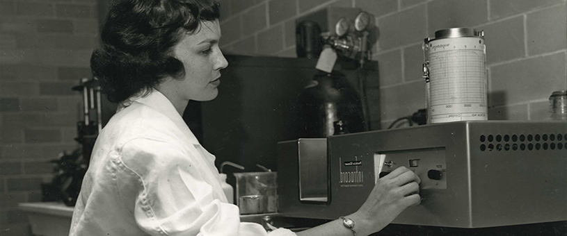 black and white photo of woman using lab equipment