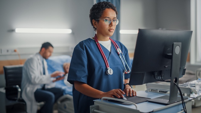 Clemson University researcher at a computer screen with a Prisma physician tending to a patient in the background