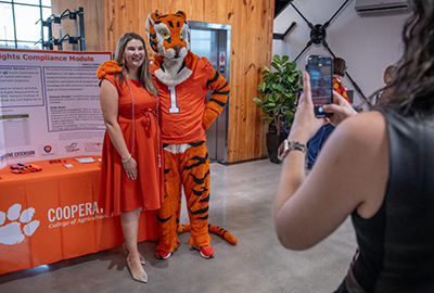 A woman in an orange dress takes a photo with the Tiger.