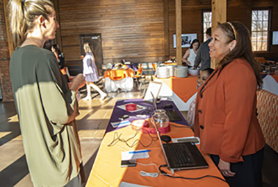 Two women have a conversation while standing over a table.