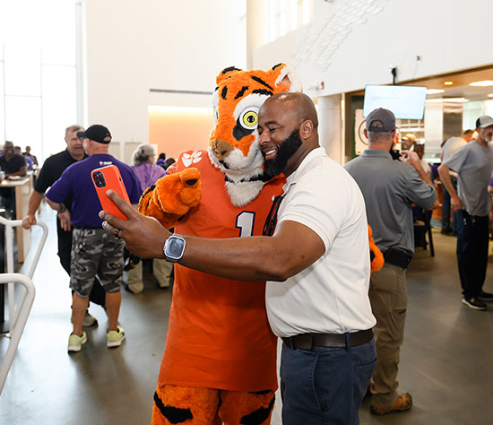 A man takes a selfie with the Tiger mascot.