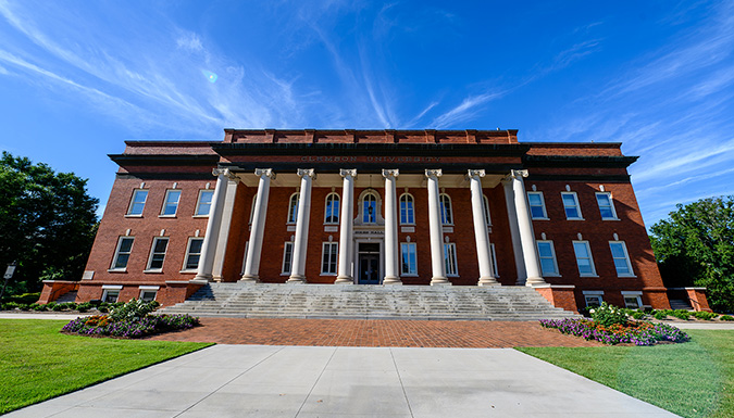 A large brick building with steps leading to a columned veranda.