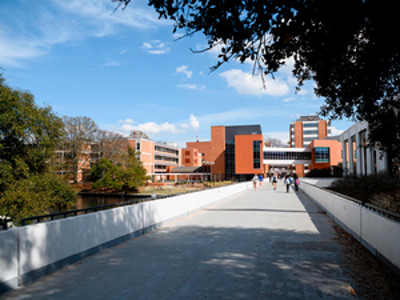 Clemson's library bridge with a blue sky above, with a few people walking ahead.