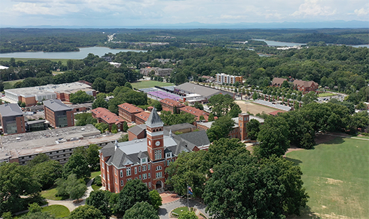 Photo taken with a drone of Tillman Hall clock tower, several nearby buildings, and the beautiful surrounding landscape.