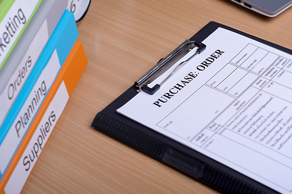 Purchase order on clipboard and binders on a desk