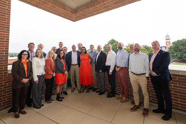 Group photo of the participants of the Clemson Chair Academy on a balcony, with a scenic view of Clemson University in the background.