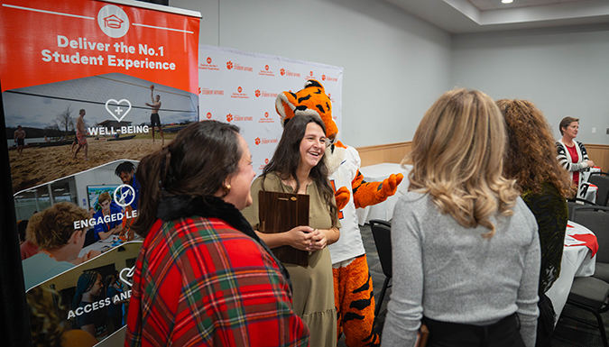 People in a conference room at an event with the Clemson Tiger celebrating Clemson Elevate goal.