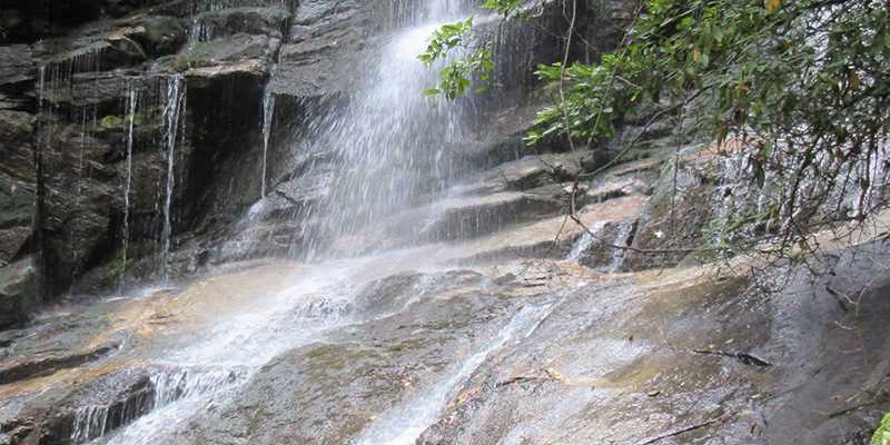 the side of a cliff with a waterfall flowing over