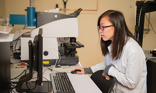 student in a lab with microscope