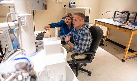 Faculty with microscope in a lab