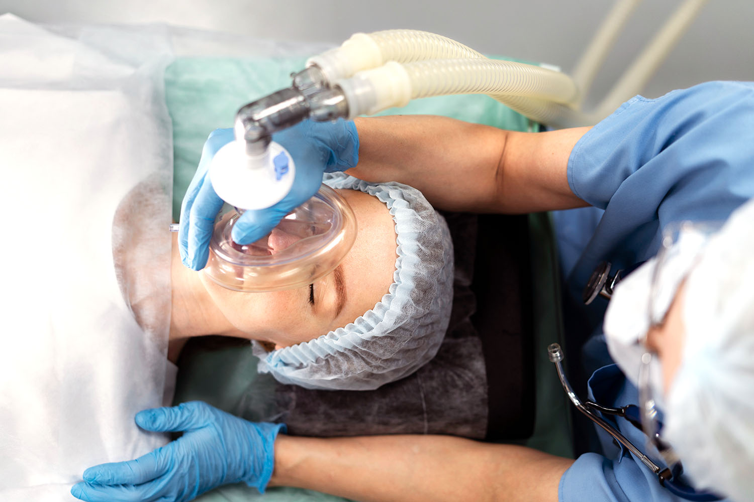 Anesthesiologist holding mask on patient in operating room.