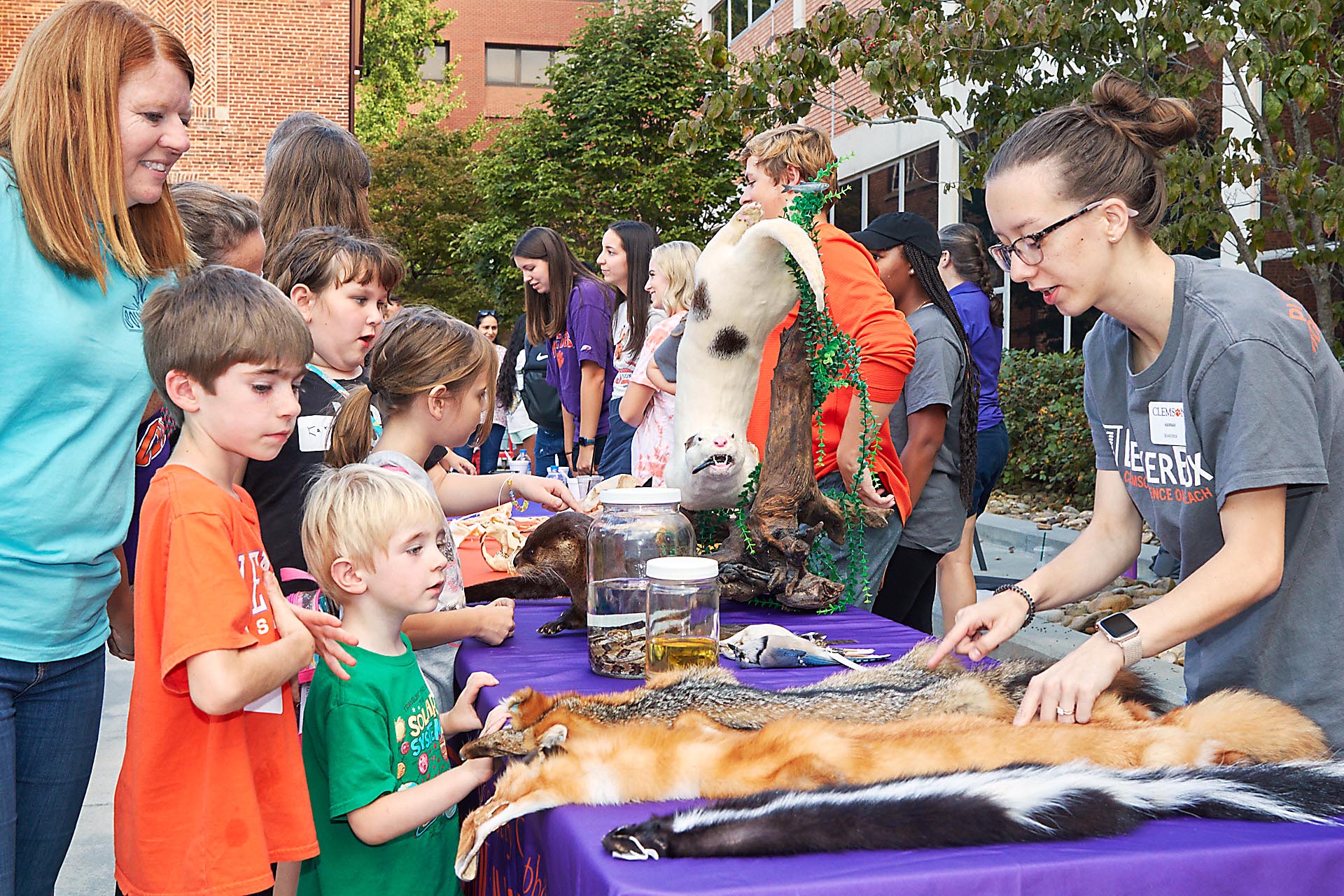 People at an event, children looking at displays of animal pelts.