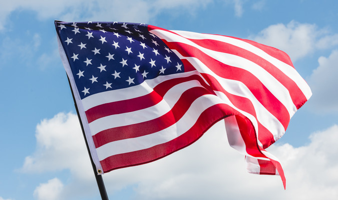 an American flag blowing in the wind on a sunny day