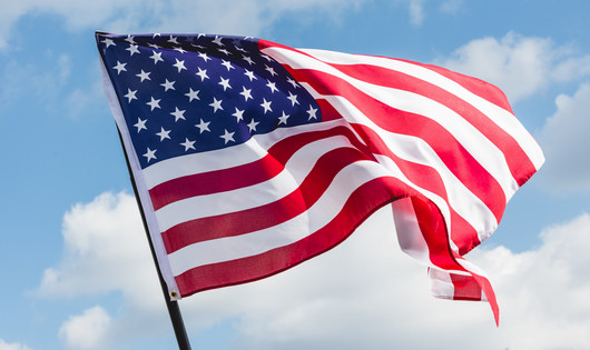 an American flag blowing in the wind on a sunny day