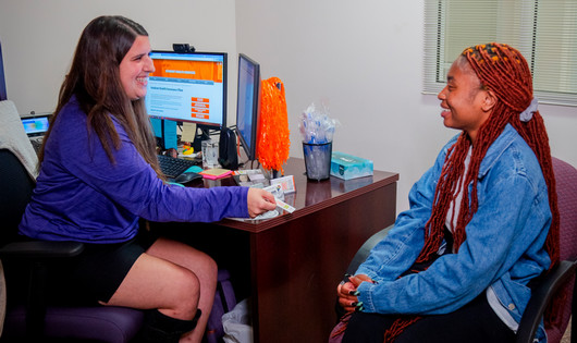 female professional sitting with a student in an office setting