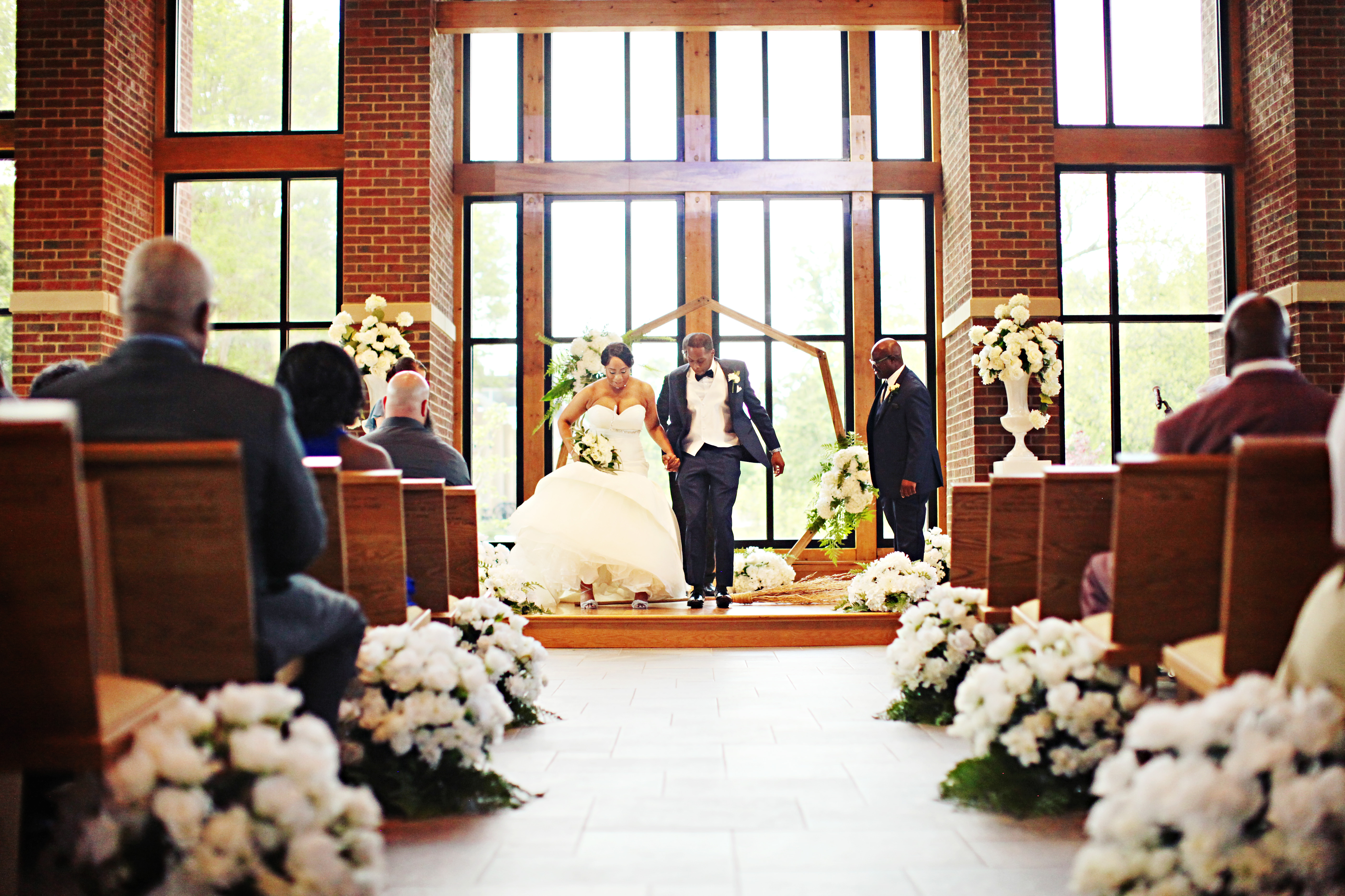 Newly wedded bride and groom jumping the broom. 