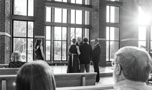 Black and white image of bride being given away by her father to be married.