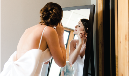 Reflection of bride getting ready in mirror. 