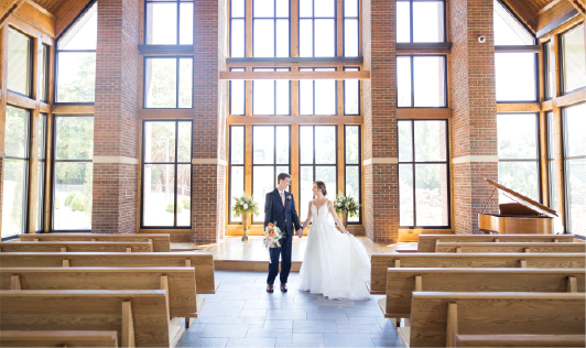 Interior of Samuel J. Cadden Chapel with a newly married bride and groom smiling at each other. 