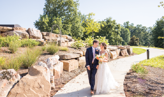 Newly wedded bride and groom walking in the Johnson Family Memorial Garden.