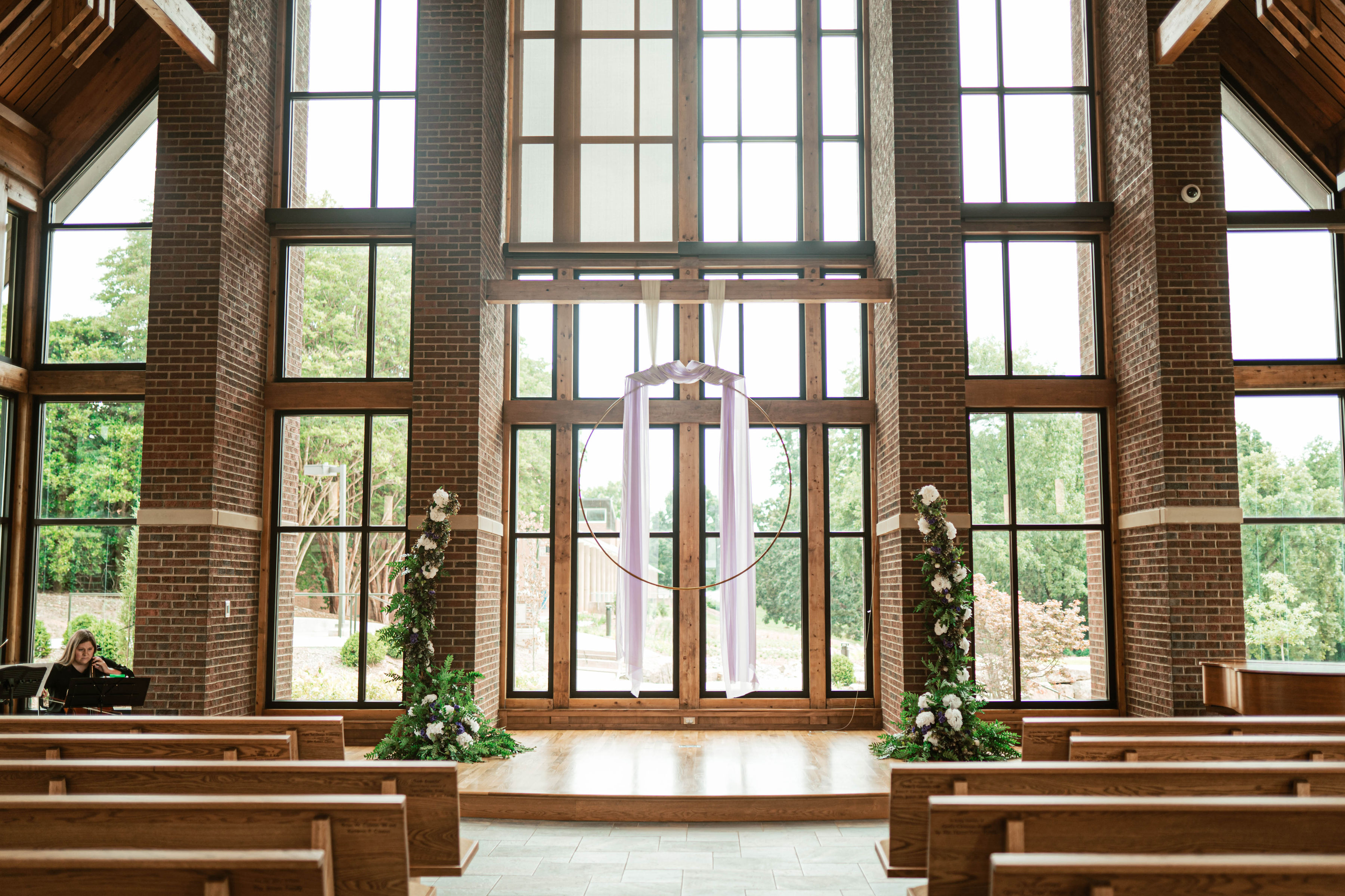 Purple drape decor hanging from the crossbeam above the platform with two white floral stands.