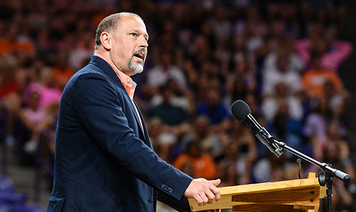 Dr. Brittain standing behind a podium addressing the crowd at convocation.